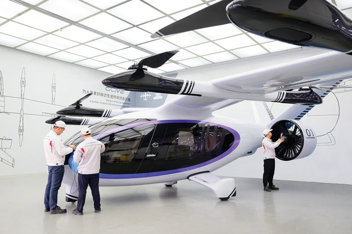 An eVTOL aircraft on a production floor with engineers inspecting components.
